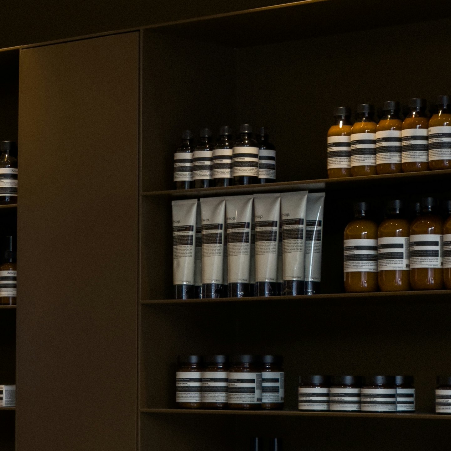 Skincare products neatly arranged on dark shelves.